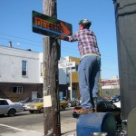 Joel striping a line at "future sea level" (photo: Hugh D'Andrade) Joel standing on a mailbox taping a sign